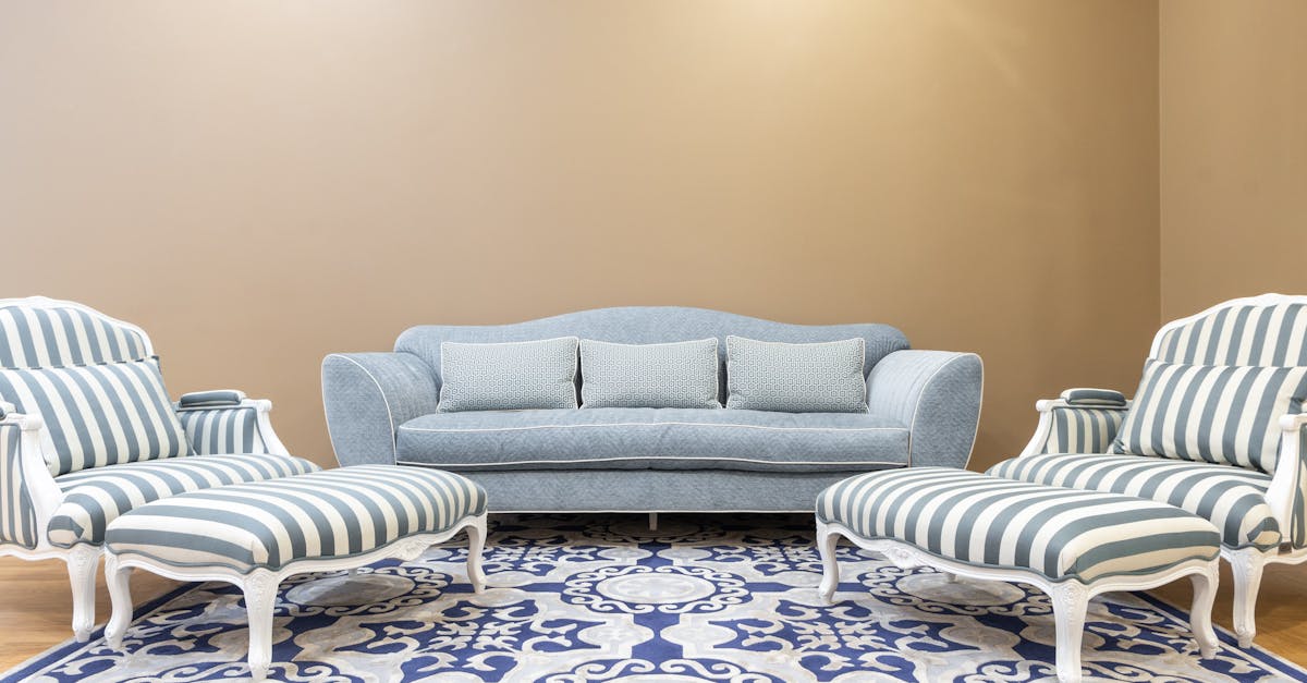Luxurious living room interior featuring a vintage blue sofa and striped chairs on a patterned carpet.